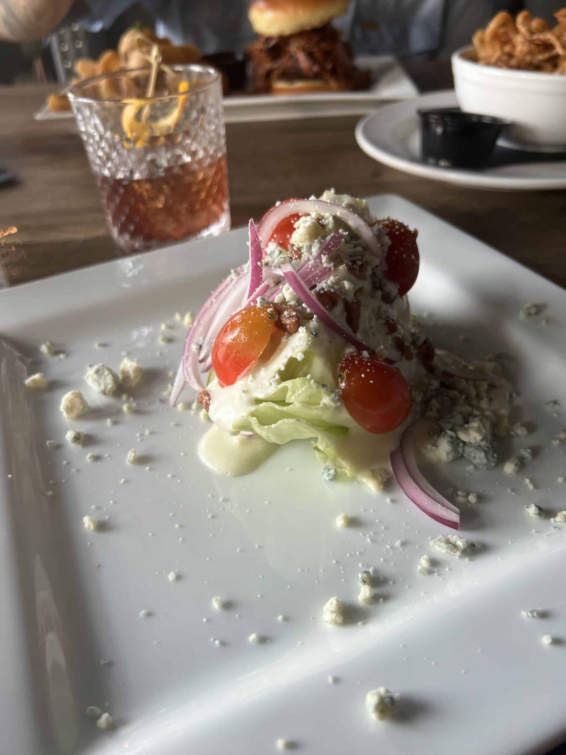 A salad on a plate containing lettuce, tomato, onion, and blue cheese.