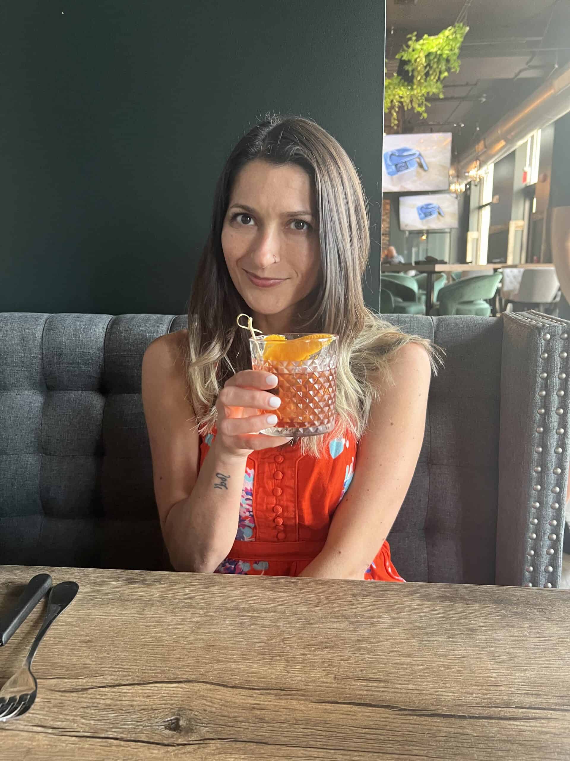 A woman smiling and holding a drink